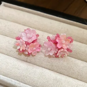 Nahaufnahme von handgefertigten rosa Harzblumen-Ohrringen mit Perlenverzierung