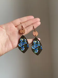 Detailed view of bohemian wooden teardrop earrings with hand-painted blue floral prints.