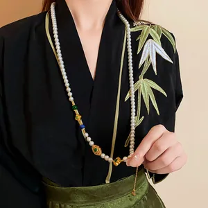 Dettaglio di una collana di perle stile cinese con lucchetto ping-an placcato oro
