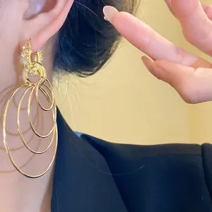 Close-up of elegant gold rhinestone multi-layer circular drop earrings on model's ear
