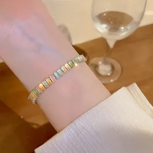 Close-up detail of a minimalist Korean style colorful zircon hand bracelet on a wrist.