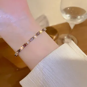 Detailed view of a gold-tone bracelet featuring colorful square and round zircons