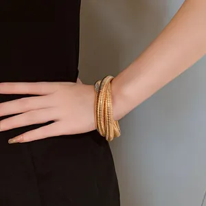 Λεπτομερής προβολή ενός ρετρό υπερβολικού χρυσού μεταλλικού βραχιολιού τριών στρώσεων
