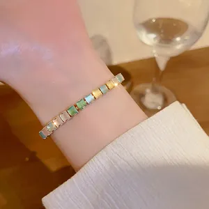 Close-up detail of an elegant colorful square-cut zircon bracelet on a delicate wrist.