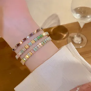 Close-up detail of three elegant multi-colored square zirconia bracelets with gold-tone finish