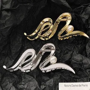 Detail view of geometric metal claw clips in gold and silver with pearl accents