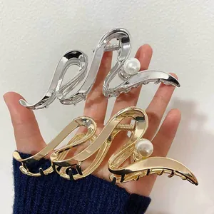 Detail shot of minimalist gold and silver geometric metal hair claws with pearl accents