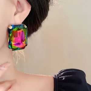 Close-up of oversized rectangular iridescent rhinestone earrings on female model
