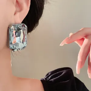 Detailed view of oversized vintage rectangular clear crystal stud earrings worn on ear