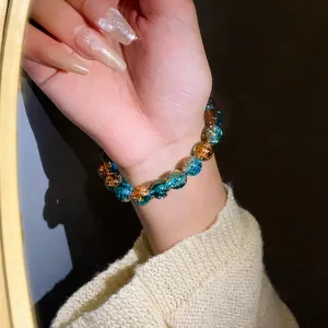 Dettaglio di un braccialetto elastico con perle in vetro cracklé blu e ambra al polso