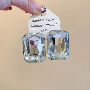 Detailed macro view of large rectangular faceted clear gemstone earrings on white card