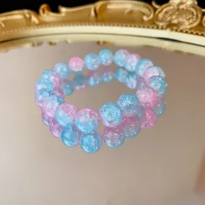 Primo piano di un braccialetto elastico con perle di vetro craquelé rosa e blu.