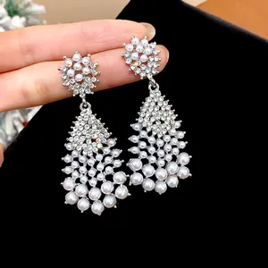 Close-up of elegant chandelier earrings with pearls and rhinestones on black velvet