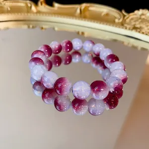 Primo piano di un braccialetto elastico con perle di vetro viola sfumate su specchio