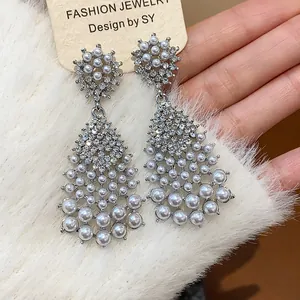 Macro view of elegant silver needle earrings with teardrop pearl and crystal tassels