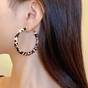 Close-up detail of leopard print leather wrapped hoop earring worn by a model