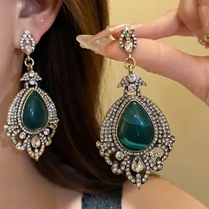 Détail de boucles d'oreilles pendantes vintage style cour en strass vert émeraude.