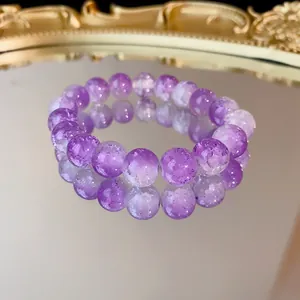 Primo piano di perle in vetro crepato sfumato viola su un braccialetto elastico.