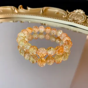 Primo piano di un braccialetto di perle di vetro craquelé arancione su uno specchio.