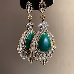 Gros plan de boucles d'oreilles vintage de style cour avec pierres vertes et cristaux
