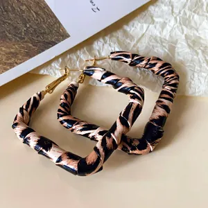 Close-up of square leopard print leather-wrapped earrings with gold-toned posts.