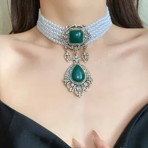 Vue rapprochée d'un collier ras du cou en perles vintage avec pendentif larme vert strass.