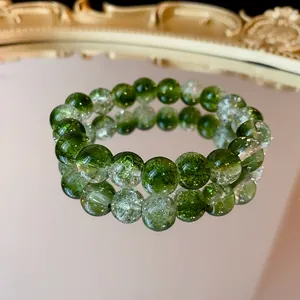 Primo piano dettagliato di un braccialetto di perle di vetro verde sfumato su uno specchio