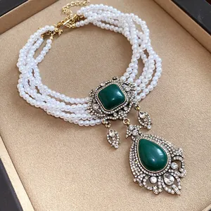 Vue détaillée du collier de perles vintage élégant avec grand pendentif vert émeraude.