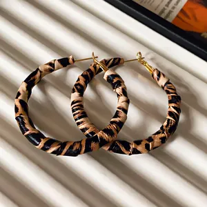 Macro view of leopard print leather wrapped geometric hoop earrings with silver needles