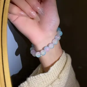 Vista dettagliata di un bracciale con perle di vetro incrinato sfumato rosa e blu al polso.