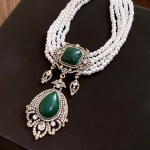 Détail d'un collier vintage style palais avec perles et pendentif goutte verte