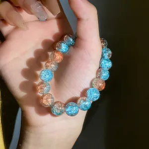 Dettaglio macro di un braccialetto di perle di vetro cracklé blu e arancione sulla mano