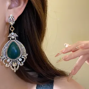 Gros plan d'une boucle d'oreille vintage avec goutte d'émeraude et strass brillants