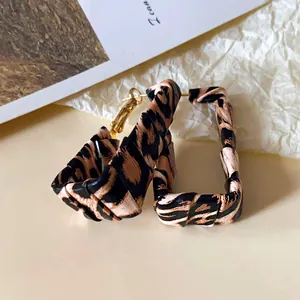 Detailed view of trendy leopard print leather wrapped hoop earrings with golden needles.