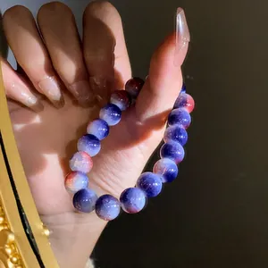 Primo piano di un bracciale con perle in vetro screpolato sfumato blu e rosso sulla mano.