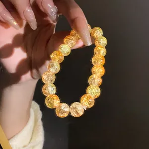 Primo piano di perle in vetro cracklé giallo sfumato su un bracciale elastico luminoso