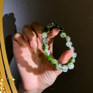 Primo piano di un braccialetto elastico in perle di vetro crackle verde sfumato a mano