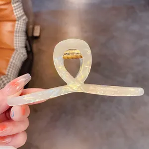 Gros plan d'une pince à cheveux élégante en acétate irisé de sirène avec ressort doré