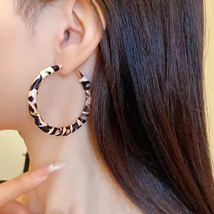 Close-up detail of large leopard print leather wrapped hoop earring on model