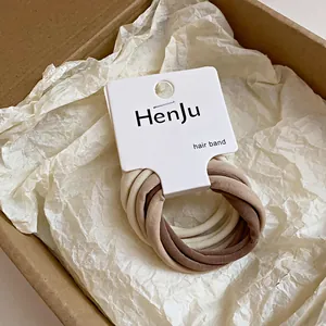 Détail d'élastiques à cheveux en tissu uni de couleur neutre dans un emballage de marque