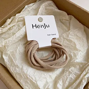 Détail de chouchous élastiques beige sur carte présentés dans une boîte cadeau
