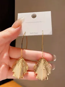 Close-up detail of golden fan-shaped tassel earrings featuring S925 silver posts on a display card