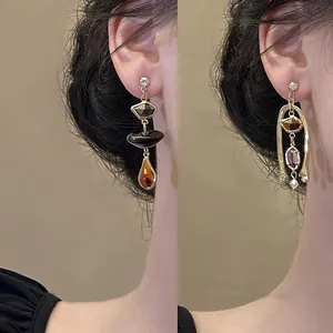 Macro view of vintage asymmetric gold earrings with zircon stones worn by a model