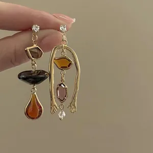 Detail view of vintage asymmetric gold earrings with amber resin and zircon accents.