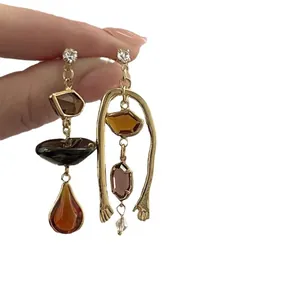 Asymmetrical vintage earrings with amber resin stones and gold hand frame design