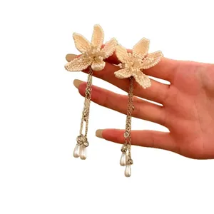 Elegant French style floral beaded earrings with long pearl tassels on hand model