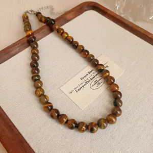 Detaillierte Ansicht einer Vintage-Tigerauge-Halskette auf einem eleganten Holztablett