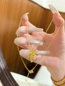 Detailed macro view of a 24k gold-plated firework flower pendant necklace on hand