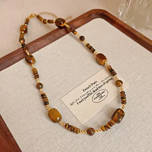 Detaillierte Ansicht einer Vintage-Tigerauge-Halskette mit Goldperlen auf einem Display