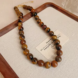 Nahaufnahme einer Halskette aus natürlichen Tigerauge-Perlen auf einem hölzernen Vintage-Tablett
